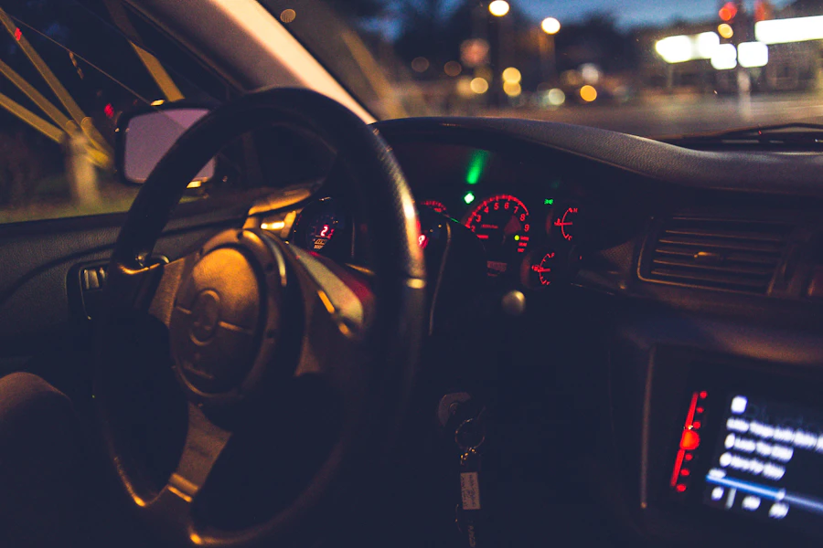Volante y tablero de un auto de noche, con luces de la ciudad visibles por el parabrisas